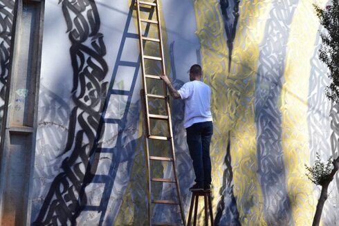 Ornamentação Caligráfica e Geométrica - Ornamentação Caligráfica Chanfrada 45°, nas cores preto e dourado, aplicada em estrutura Geométrica, sobre fundo cinza. Caligrafite. Arte Mural.